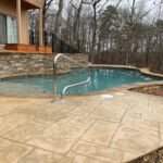 Concrete pool deck with natural stone coping